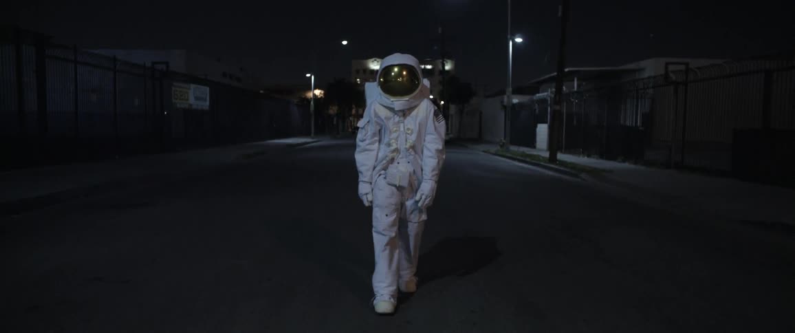 A man dressed as an astronaut walking down an empty city street