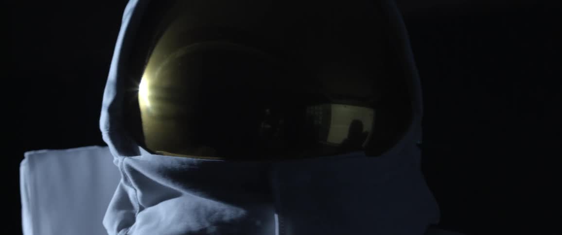 Astronaut with a gold helmet looking around a dark area