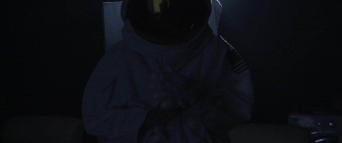 Silhouette of a person wearing an astronaut suit stands in front of the camera