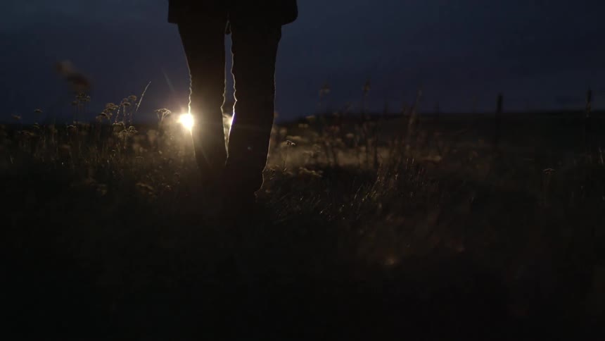 A person walks towards headlights from a vehicle