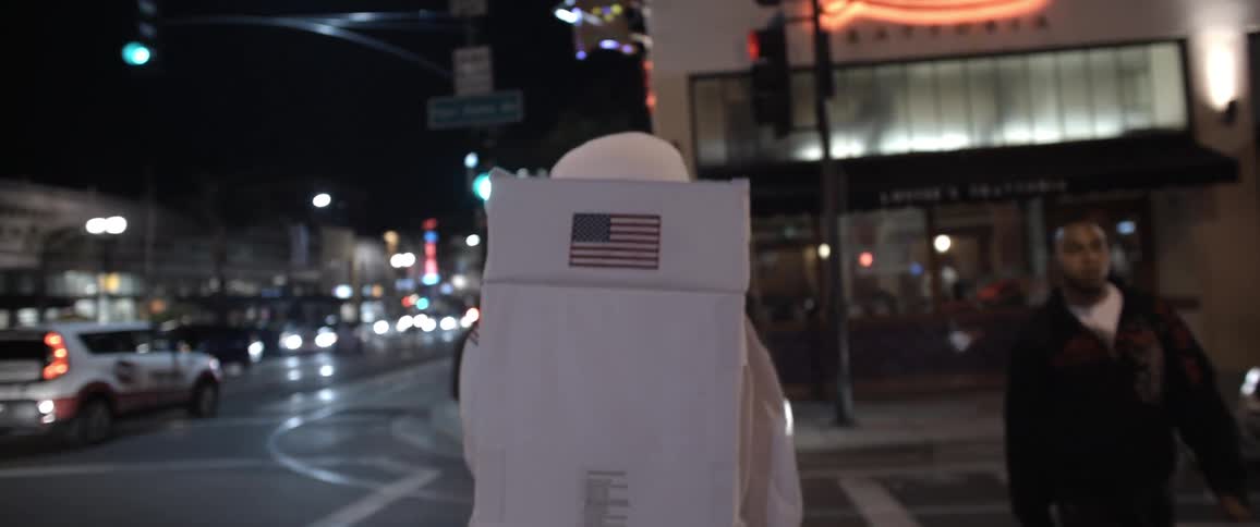 Person dressed as an astronaut, crosses a busy city street intersection