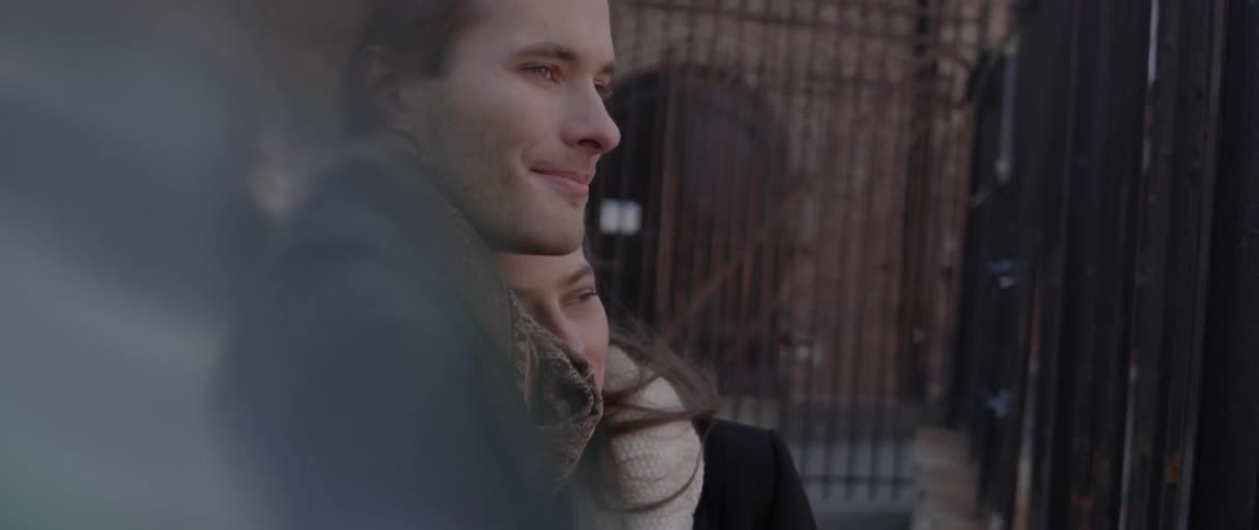 A young man and woman kiss as they watch on outside