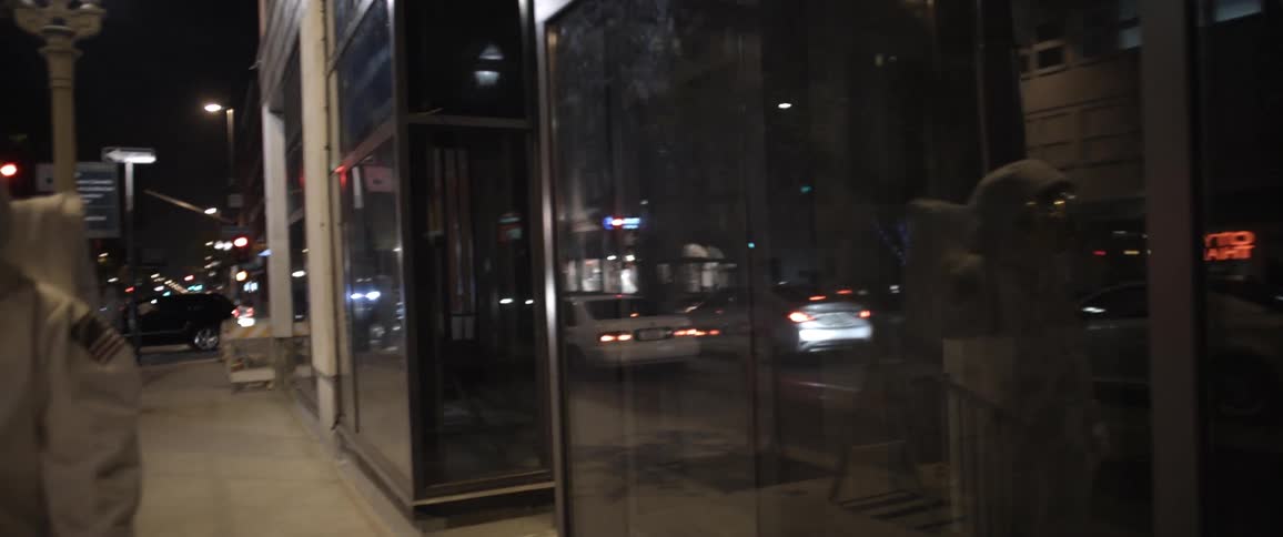 An astronaut walks down a city street at night