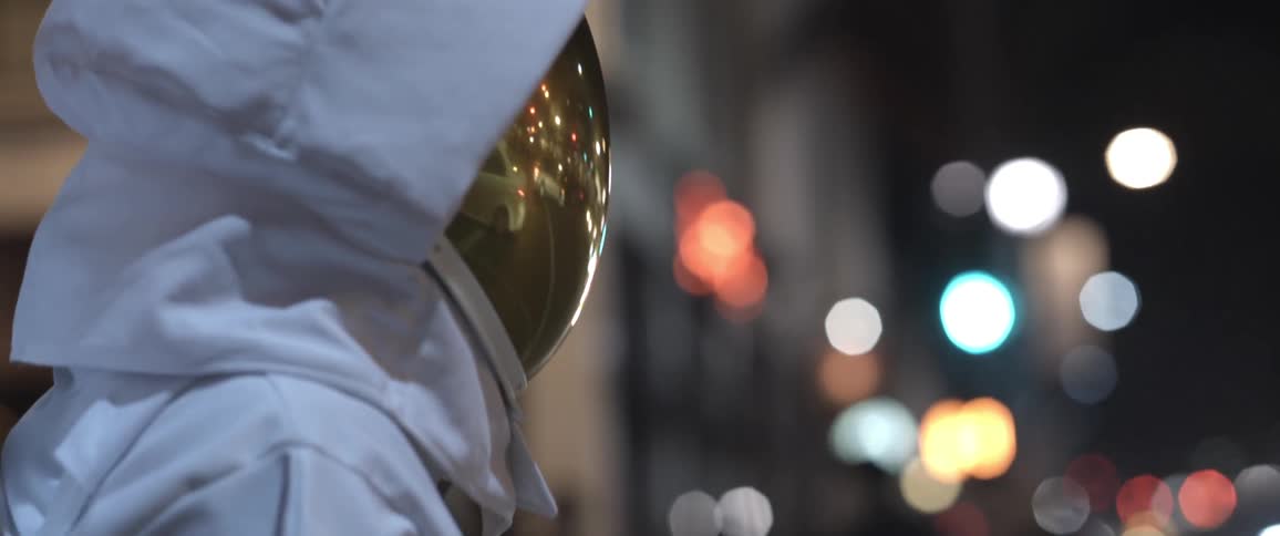 A man in an astronaut suit standing on the sidewalk at night