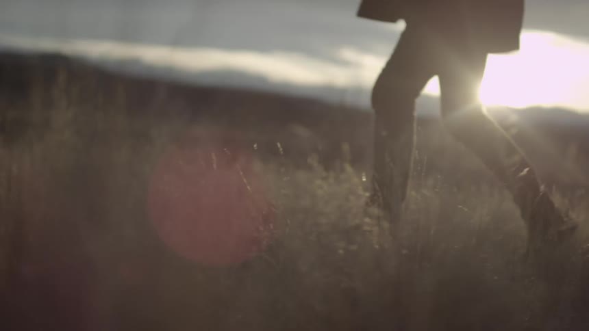 A woman walks slowly on an open field