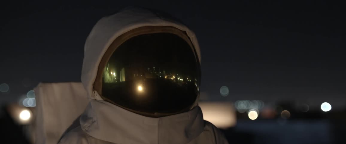 Someone dressed as an astronaut peering towards a flashing light
