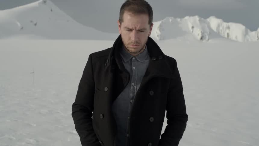 A man in a coat stands in a field of snow