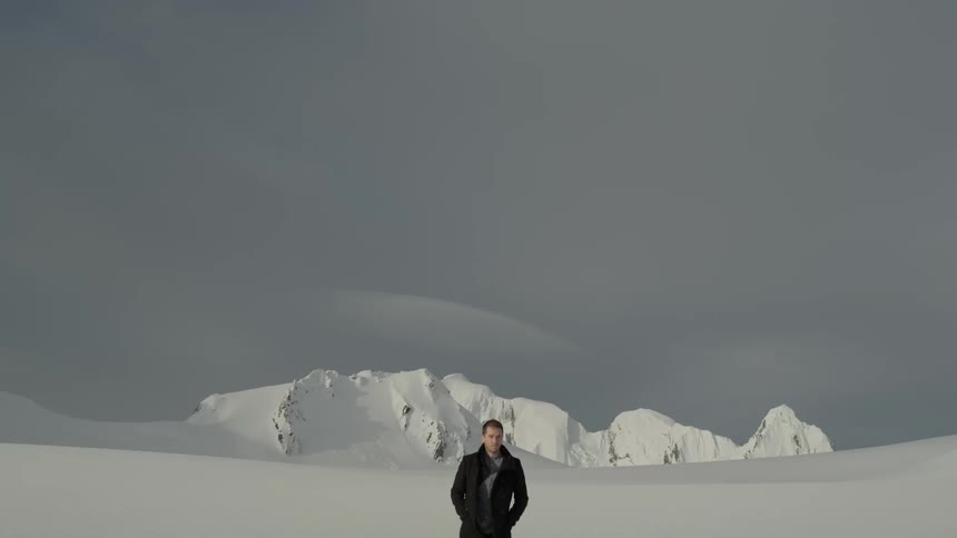 Man walks through snowy landscape towards camera