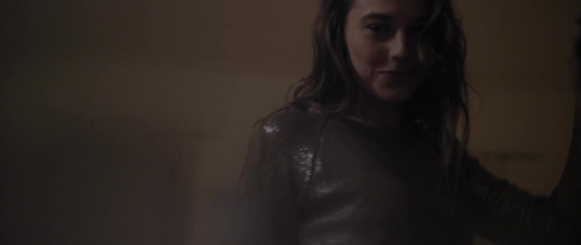 A young woman in a shiny blouse dancing in a room