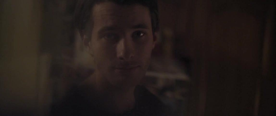A young man with light facial hair turns to face the camera