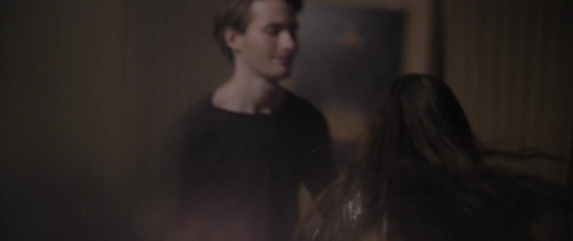A young man and woman smile as they dance