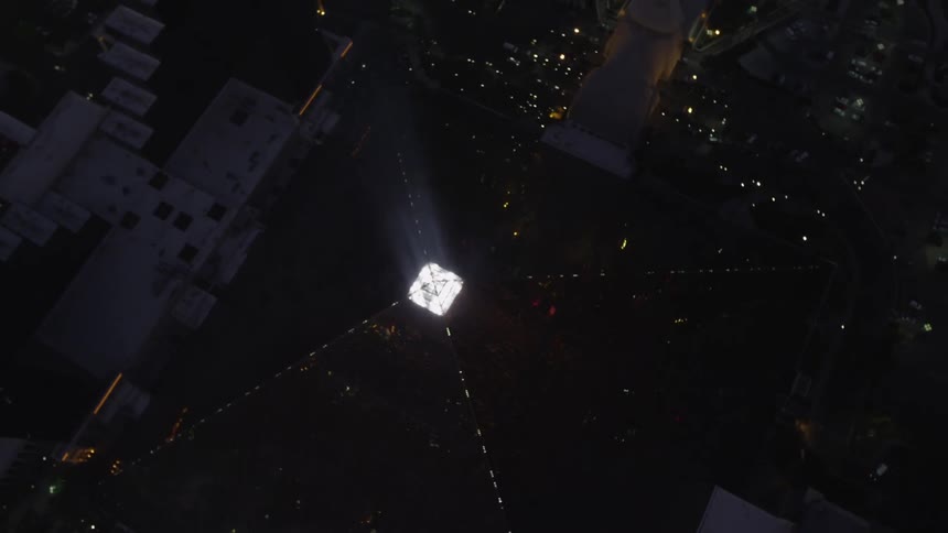 Top down view of a pyramid shaped glass building lit up at night