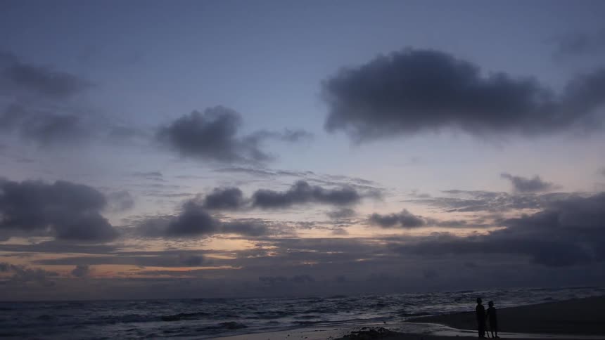 People standing on a beach at sunset