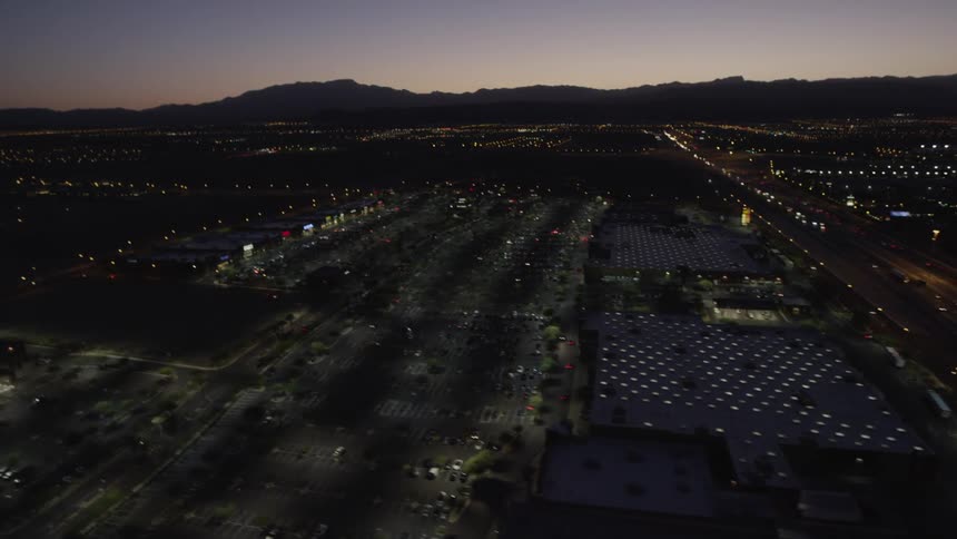A helicopter view of a city with its lights on during sunset