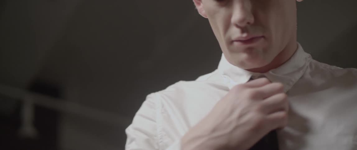 Man adjusting the collar of his shirt putting on a tie