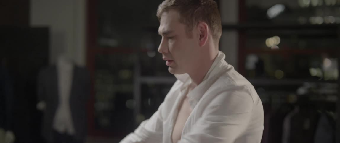 Tattooed man putting on a dress shirt