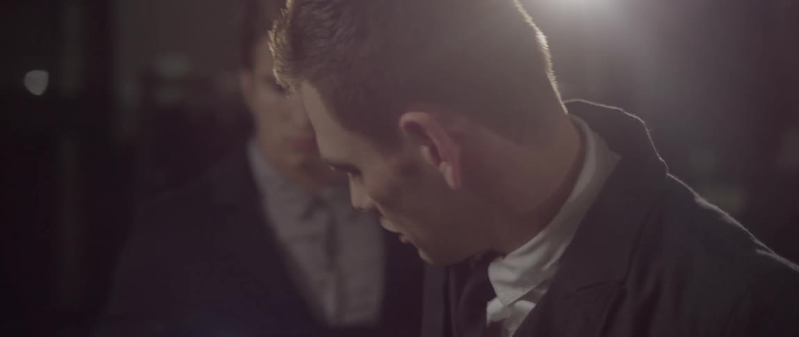 Men in suit gets help wearing his coat in a dressing room