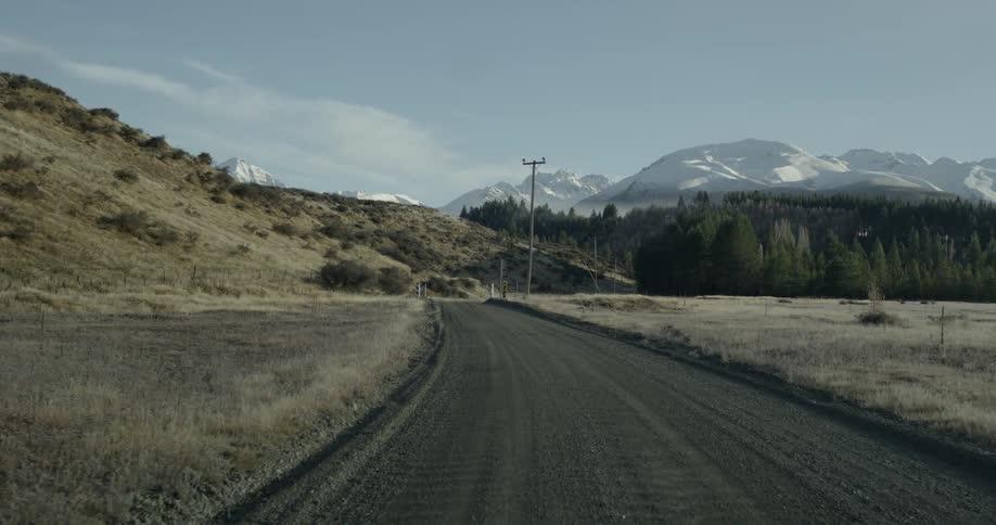 Slowly traveling down a road in an open area with a hill