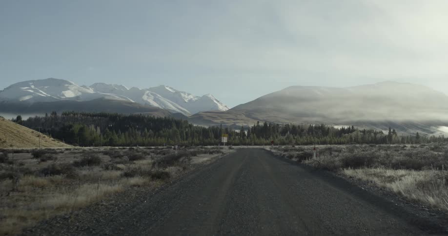 A dirt road leads to the mountains