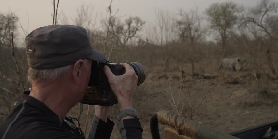 Man photographing a rhinoceros in the wild