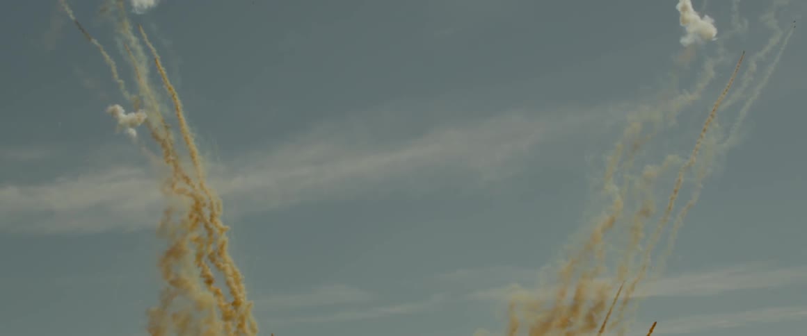 Colored smoke shoots upward into the sky