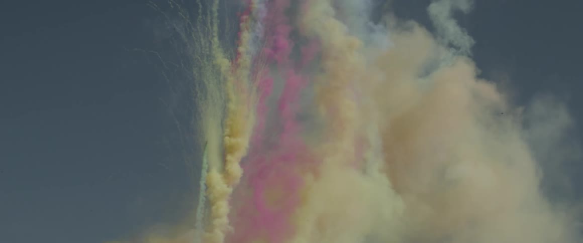 Colored smoke shoots upward into the sky