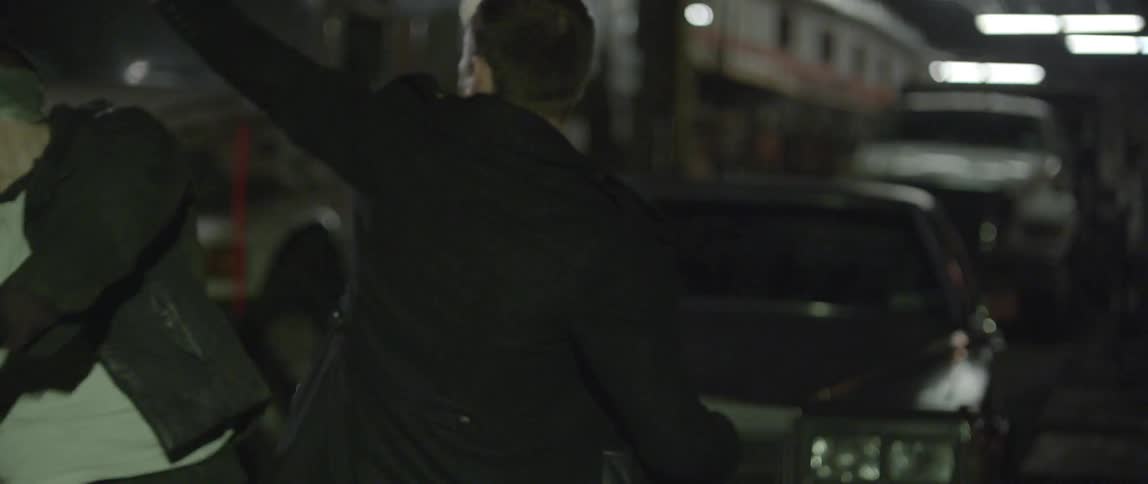 A man in a long black coat fights off attackers