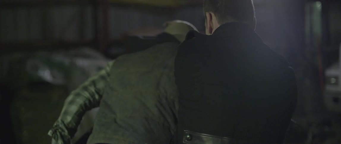A man in a long black coat fights off attackers