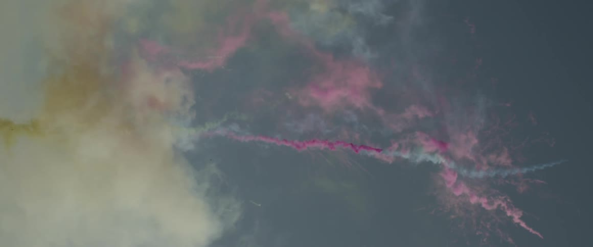 Cans of colored smoke fly through the sky above