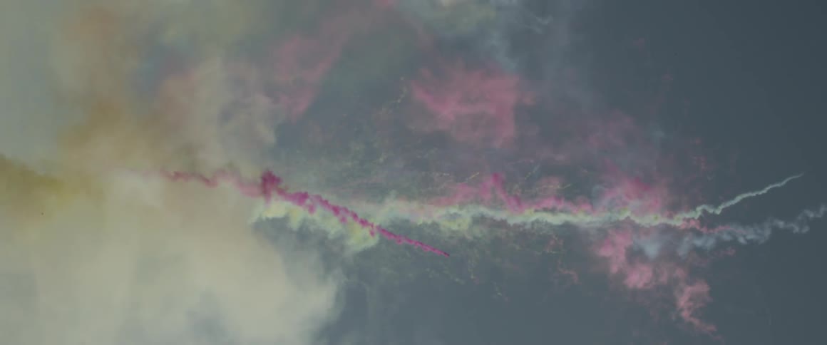 Colored smoke shoots upward into the sky
