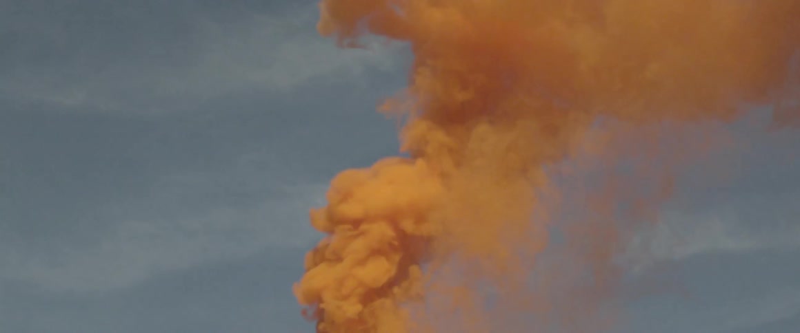 Colored smoke shoots upward into the sky