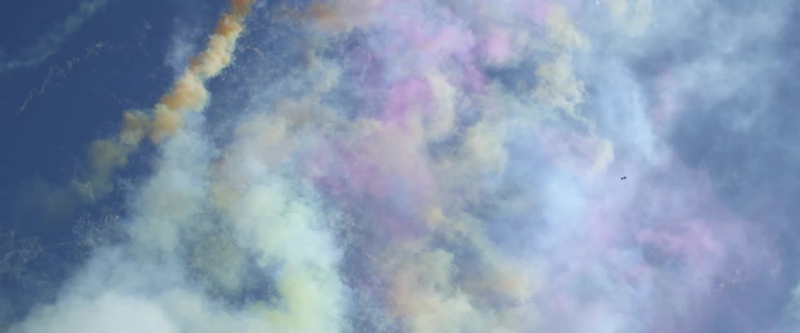 Colored smoke shoots upward into the sky