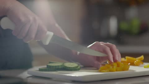 Vegetables being sliced on a cutting board in a kitchen