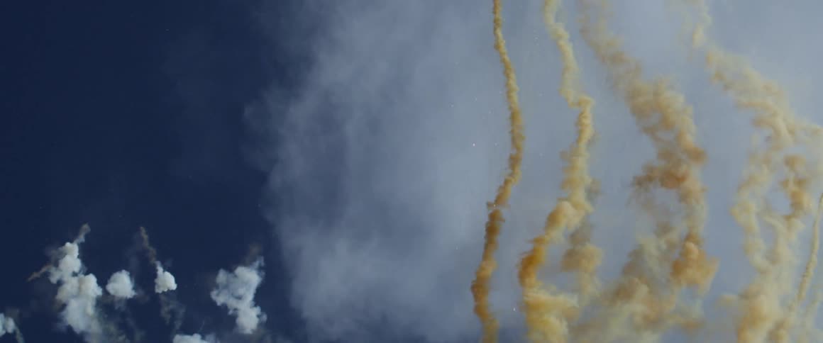 Colored smoke shoots upward into the sky
