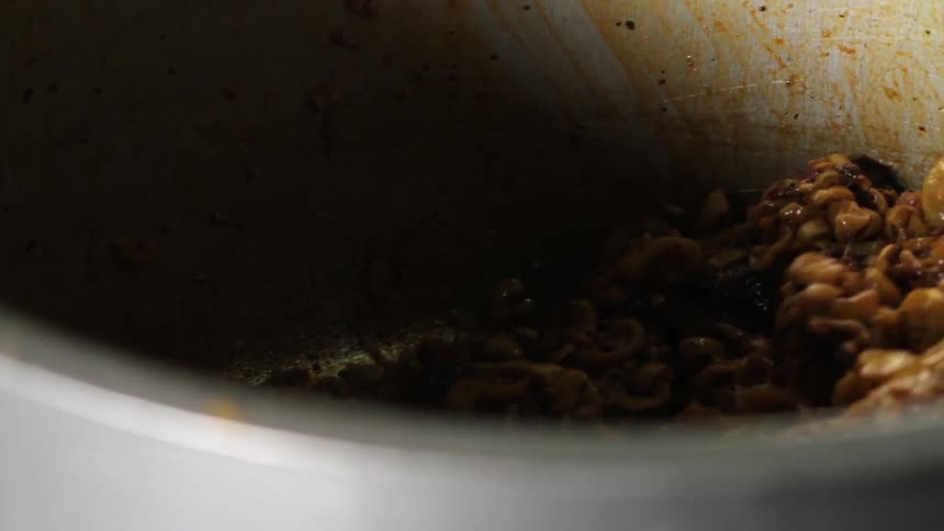 A dish of lentils in a pot being stirred by a flat spoon