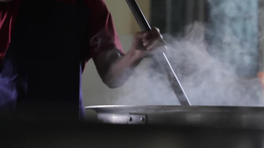 A worker stirs a steaming bowl