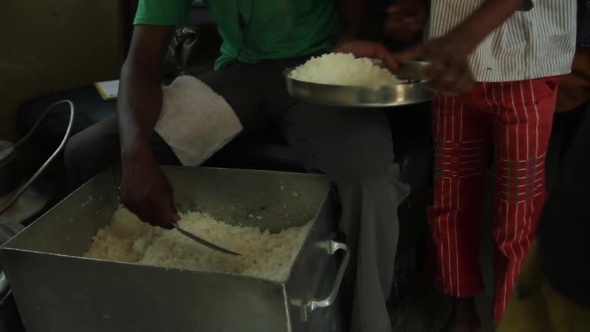 Rice in a large bin is stirred and dished up