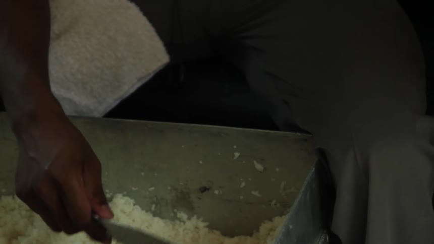 A man scoops rice into metal containers and hands them to someone off camera