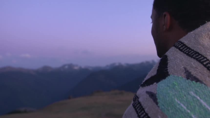 A man listens to music on a cliff