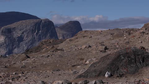 A hill terrain covered with rocks and dirt being seen with clouds over it
