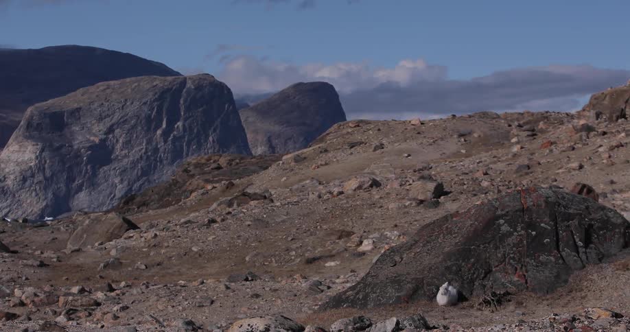 A hill terrain covered with rocks and dirt being seen with clouds over it