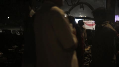 People surround an outdoor market at night