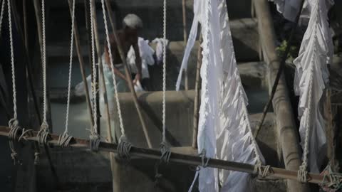 Shirtless man cleaning his clothes on a ship