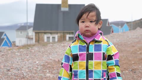 A toddler stands outside in the breeze