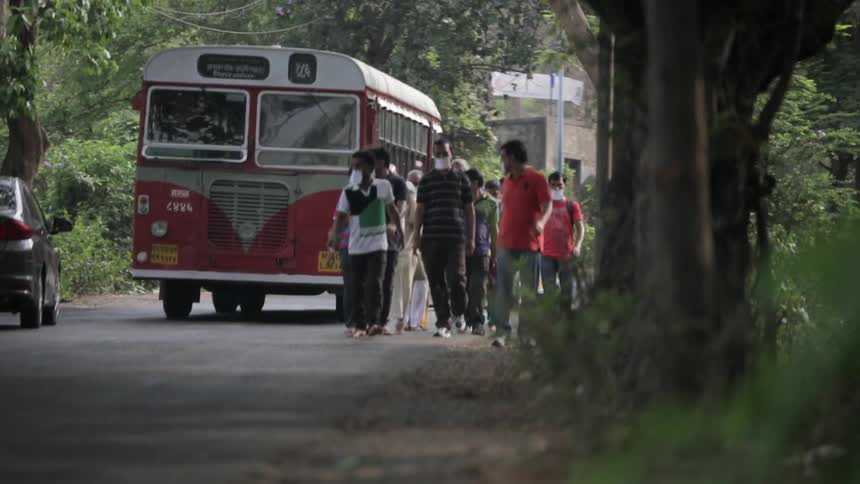 People walk down a shaded road as vehicles pass by