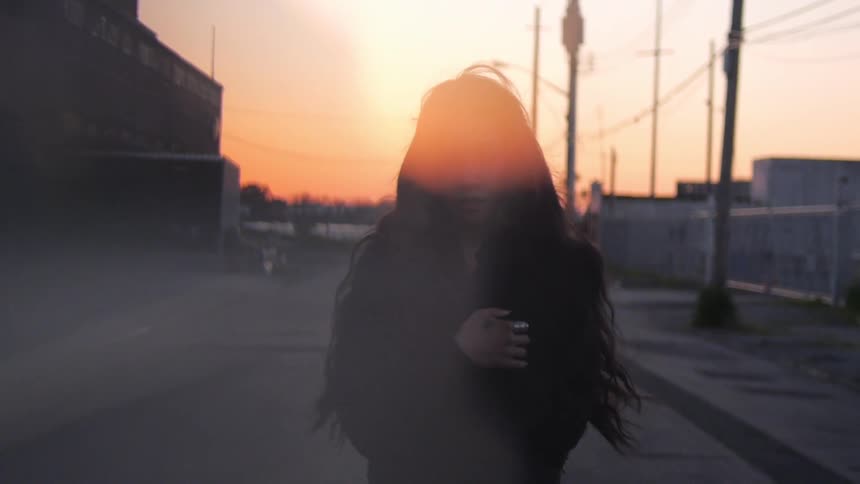 A woman stands in front of a sunset