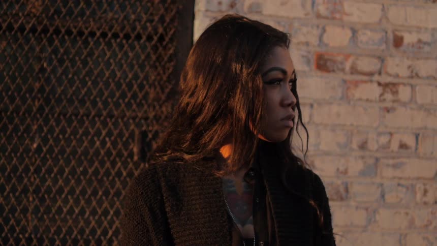A woman stands near a wall