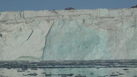 Ice chunks float on the surface of the water near a wall of ice