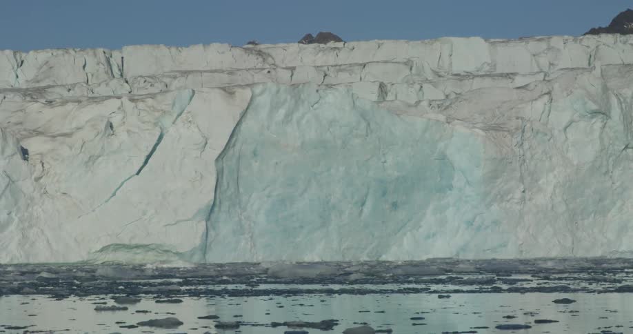 Ice chunks float on the surface of the water near a wall of ice