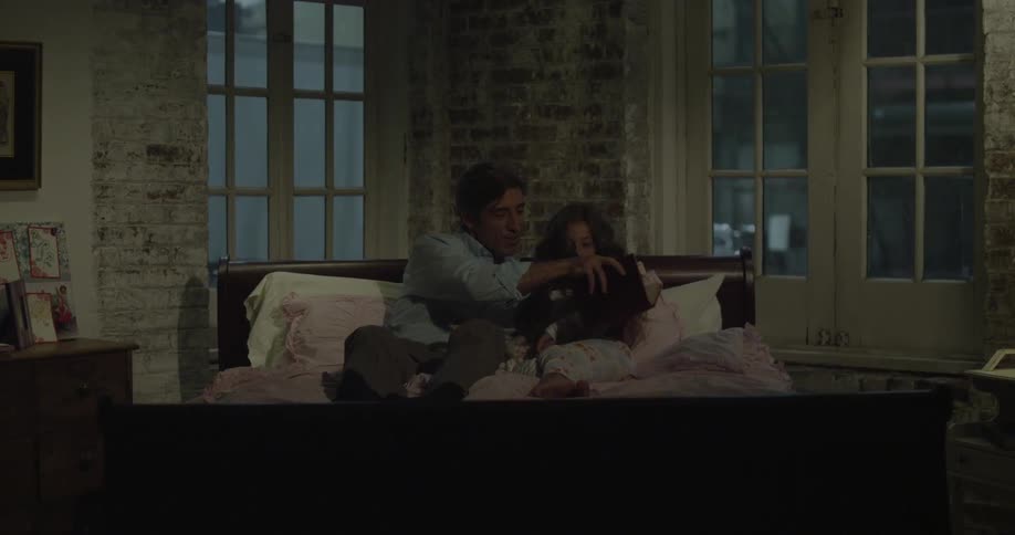 Man and girl sit down on a bed and read a book